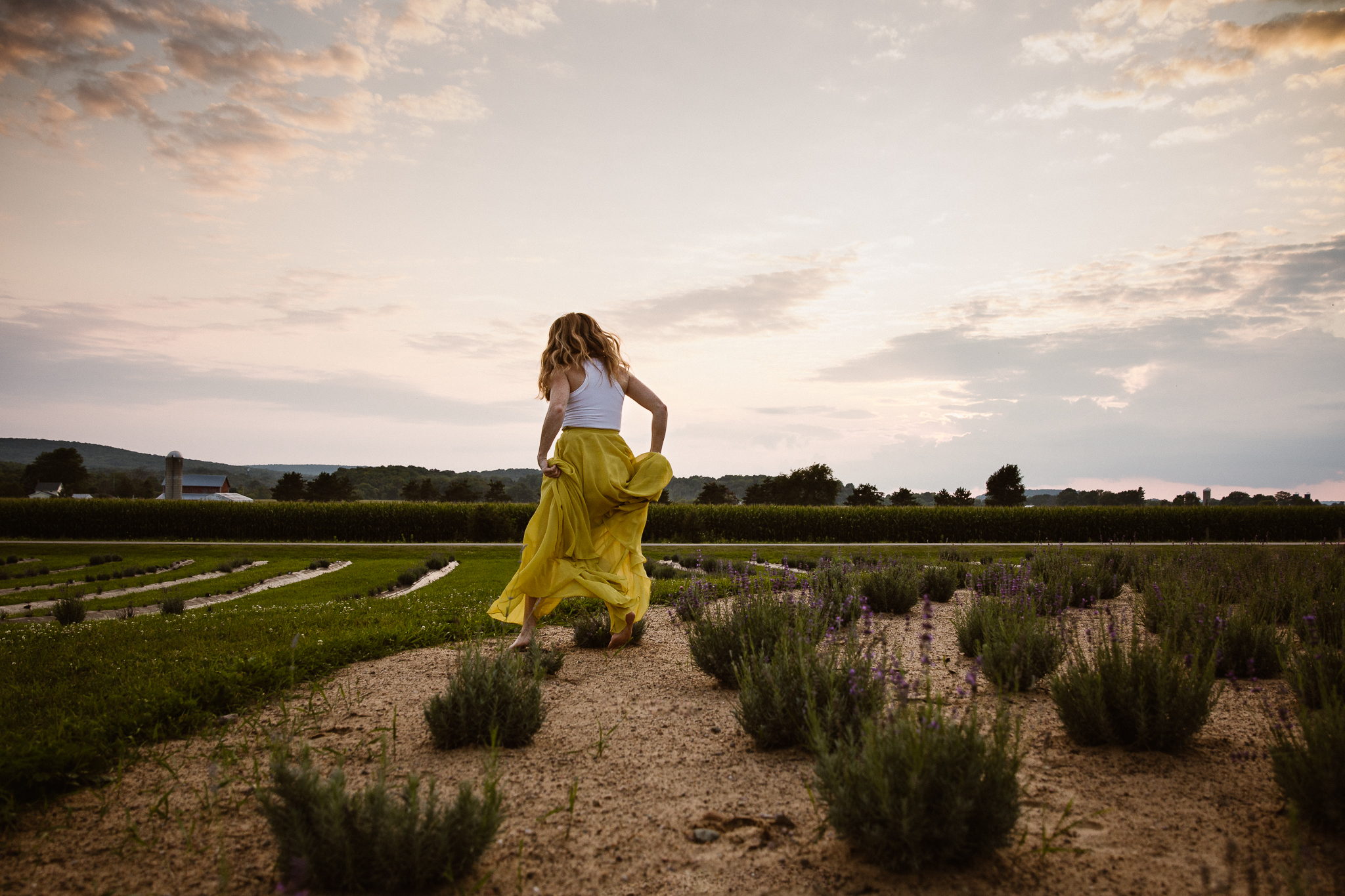 Red headed woman in yellow skirt at sunset in a lavender field.
